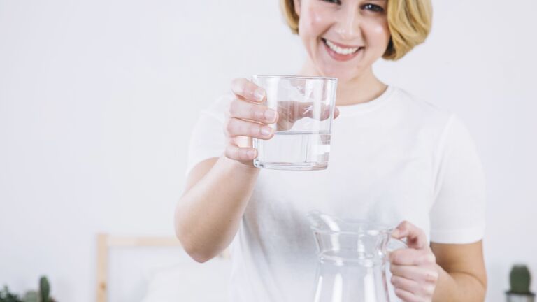 Frau trinkt Wasser aus Glas