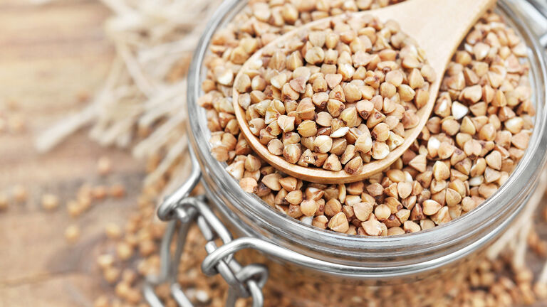 Glas mit Buchweizen und Holzlöffel drin