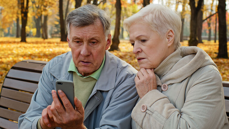 verärgertes älteres Paar schaut auf Smartphone