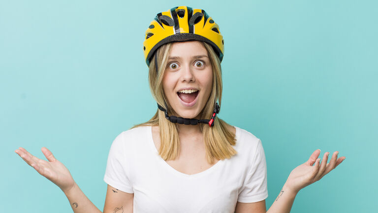 Glücklich und erstaunt schauende Frau mit einem Fahrradhelm auf dem Kopf