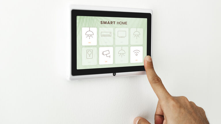 Eine Hand mit ausgestrecktem Zeigerfinder berührt ein Tablet zur Steuerung des Smarthome