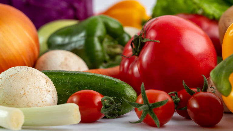 Tomate, Zucchini, Lauch, grüne Paprika, Rotkohl und eine Zwiebel von der Seite fotografiert