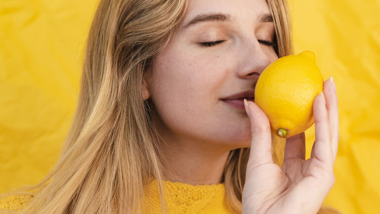 Junge Frau riecht an einer Zitrone