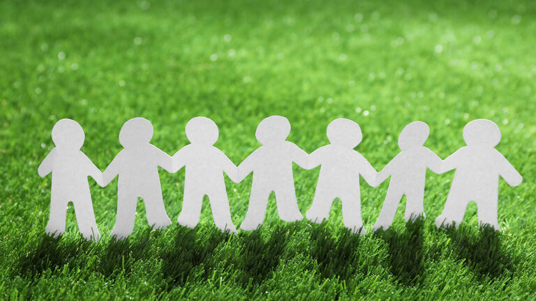 Scherenschnitt-Papiermännchenkette auf einer Wiese