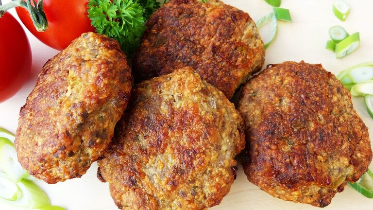 Mehrere gebratene Frikadellen mit Petersilie und Tomate
