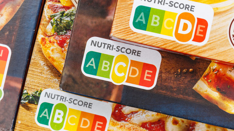 Drei verschiedene Lebensmittelverpackungen mit der Lebensmittelampel "Nutri-Score": Einmal mit der Nutri-Score-Bewertung "B", einmal mit der Nutri-Score-Bewertung "C" und einmal mit der Nutri-Score-Bewertung "D".