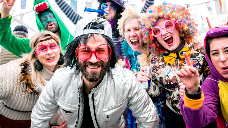 Mehrer bunt und lustig verkleidete Frauen und Männer stehen für ein Gruppenfoto zusammen und feiern Fasching.