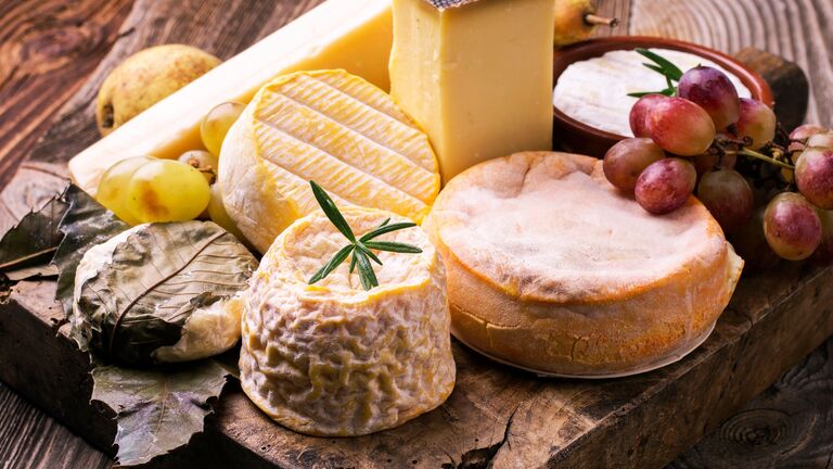 Käseplatte mit mehreren Käsestücken und Trauben als Dekoration