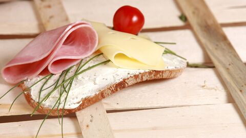 Brot mit Schinken und Käse belegt und Tomate und Schnittlauch garniert