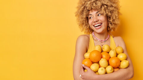 Ein junge Frau hält Zitronen und Orangen in ihren Armen