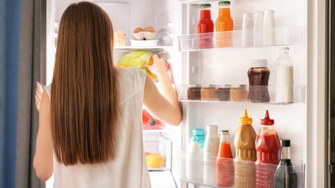 Frau schaut in geöffneten Kühlschrank