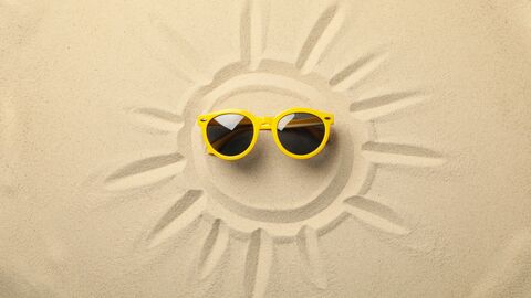 In Sand gemalte Sonne mit Sonnenbrille