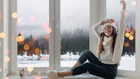 Glückliche Frau am Fenster mit Winterlandschaft