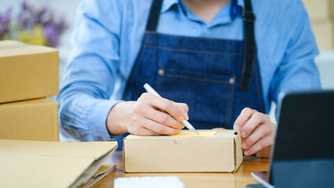 Ein Mann beschriftet eine Paketkarte auf einem Paket