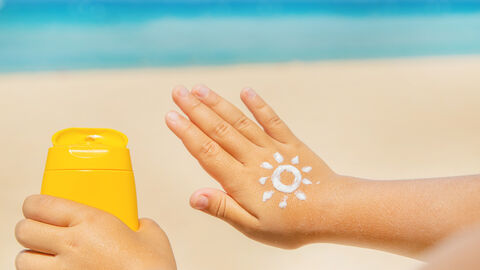 Kinderhand mit einer Sonnencreme Sonne verziert