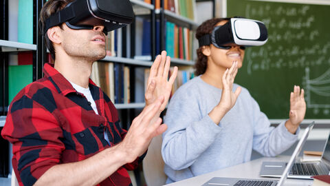 Ein junger Mann und eine junge Frau probieren eine Virtual Reality Brille aus