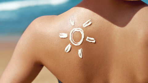 Auf dem Rücken einer Frau ist mit Sonnencreme eine Sonne gemalt