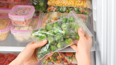 Frau holt Tiefkühlkost aus dem Gefrierschrank