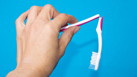 Eine zerbrochene Zahnbürste wird von einer Hand gehalten