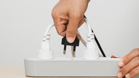 Eine Hand drückt einen Stecker in eine Mehrfach-Steckdose