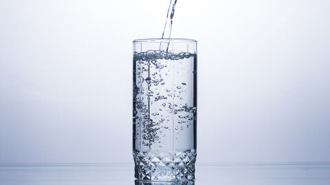 Wasser wird in Glas geschüttet