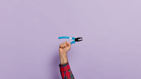 Eine Hand hält eine Zange empor