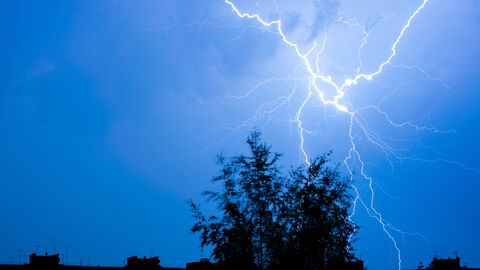 Gewitter, Starkregen und Sturm: Schutzmaßnahmen bei Unwetter Blitze über einer Stadtsilhouette