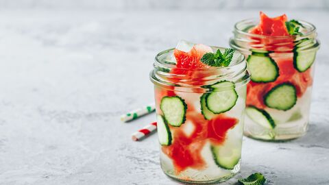 Zwei Gläser mit Wasser mit Gurke und Wassermelone Zwei Gläser mit Wasser mit Gurke und Wassermelone