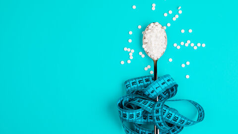 Süßungsmittel-Tabletten in Teelöffel umwickelt mit Maßband