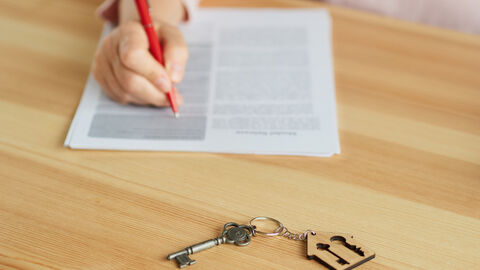 Frau unterschreibt einen Vertrag neben einem Wohnungsschlüssel