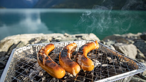 Viel Müll für wenig Geschmack Drei Bratwürstchen liegen auf einem Einweggrill
