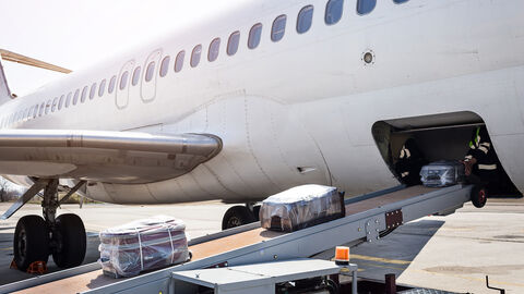 Koffer werden in einen Flugzeugrumpf eingeladen