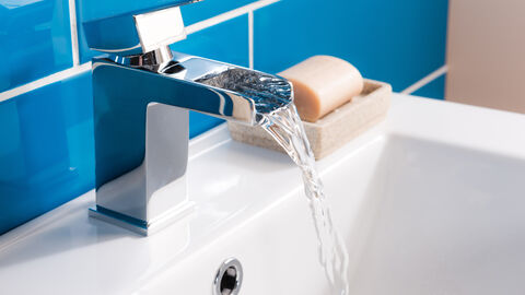 Laufender Wasserhahn am Waschbecken eines Badezimmers