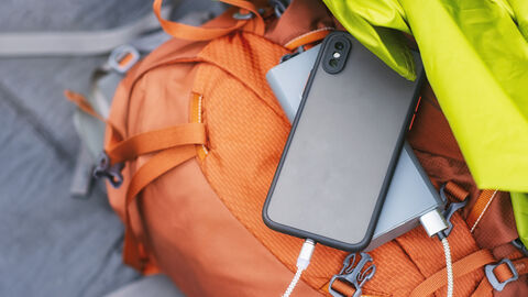 Smartphone und Powerbank liegen auf einem Rucksack