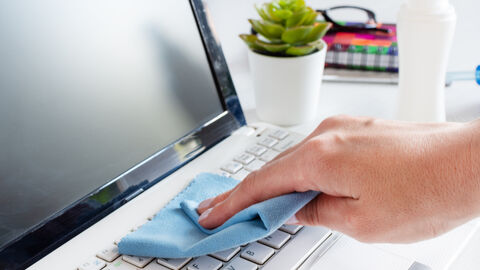 Eine Hand wischt mit einem Tuch über eine Tastatur