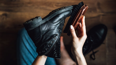 Person putzt Lederschuh mit einer Bürste