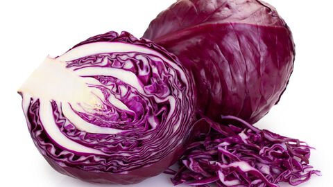 Ein angeschnittener Rotkohlkopf und gehobelte Rotkohlblätter, im Hintergrund ein ganzer Rotkohlkopf