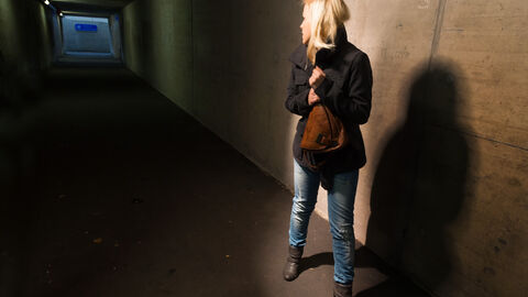 Frau im Tunnel hat Angst Blonde Frau mit Handtasche nacht im Tunnel dreht sich um, um zu schauen ob jeman dhinter ihr ist. Sie hat Angst.