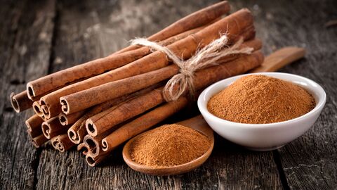 Zimt in Stangen- und Pulverform zusammengebundene Zimtstangenn und Zimtpulver in zwei Schalen