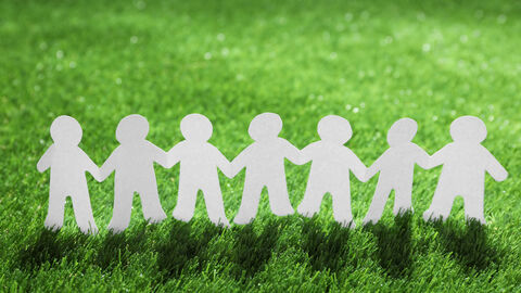 Scherenschnitt-Papiermännchenkette auf einer Wiese