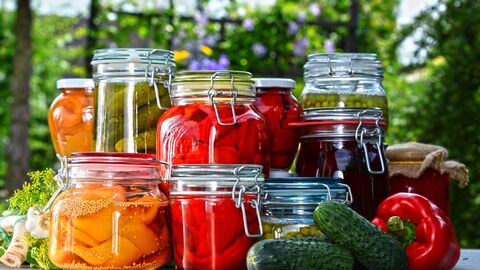 Mehrere Gläser mit eingemachtem Obst und Gemüse wie Pfirsiche, Essiggurken, Paprika, Erbsen