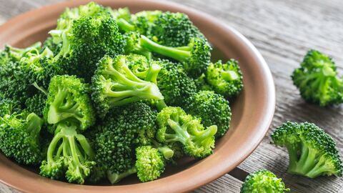 Brokkoliröschen liegen in und neben einer Holzschale