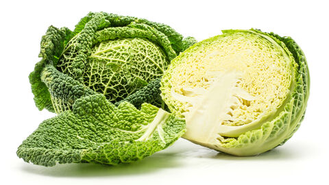 Ein Wirsingkohl und daneben ein halbierter Wirsingkohl. Im Vordergrund liegt ein Kohlblatt.