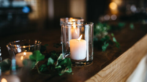 Kerzen im Glas auf einem Holzbrett