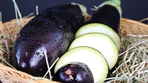 Ganze und in Scheiben geschnittene Aubergine liegen in einem Korb