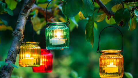 Bunte Windlichter hängen in einem Baum in der Abenddämmerung