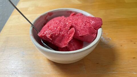 Selbstgemachtes Beereneis in einer Porzellan-Schüssel mit Löffel.