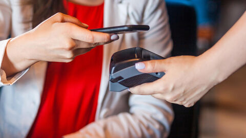 Eine Frau bezahlt mit Hilfe ihres Smartphones