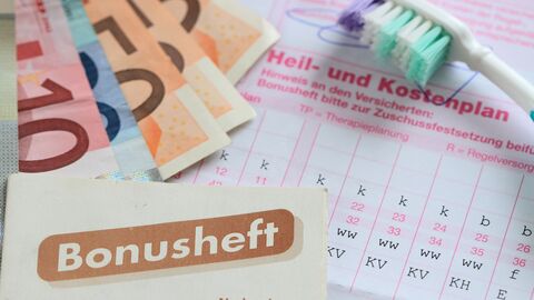 Bonusheft, Geldscheineund Zahnbürste liegen auf einem Heil- und Kostenplan