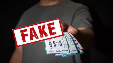 Ein Mann hält fünf Konzertkarten in der Hand. Ein Stempel-Motiv liegt über diesem Bild mit der Aufschrift FAKE.